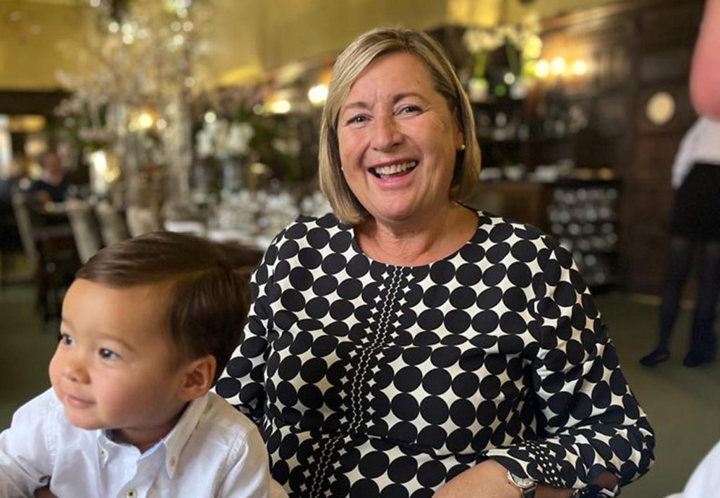 Photo of Judith Henstock with her grandson on her lap. She's happy and smiling at the camera.